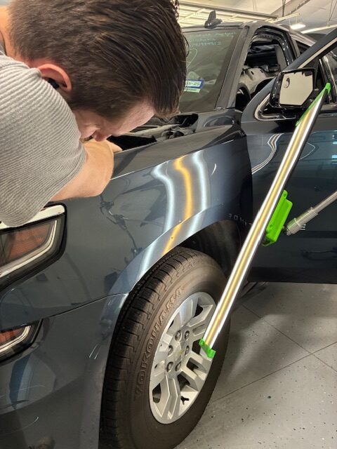 A man is working on the side of his car.