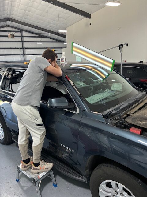 A man is fixing the hood of his truck.